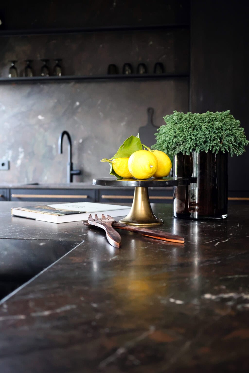 Küche: Black Kitchen – dunkle Arbeitsplatte mit Zitronenschale vor steinerner Rückwand