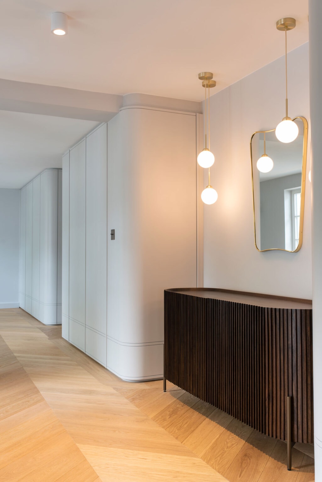 Projekt: Modern Living – Flur mit gerundeten weißen Einbauschränken und dunklem Sideboard