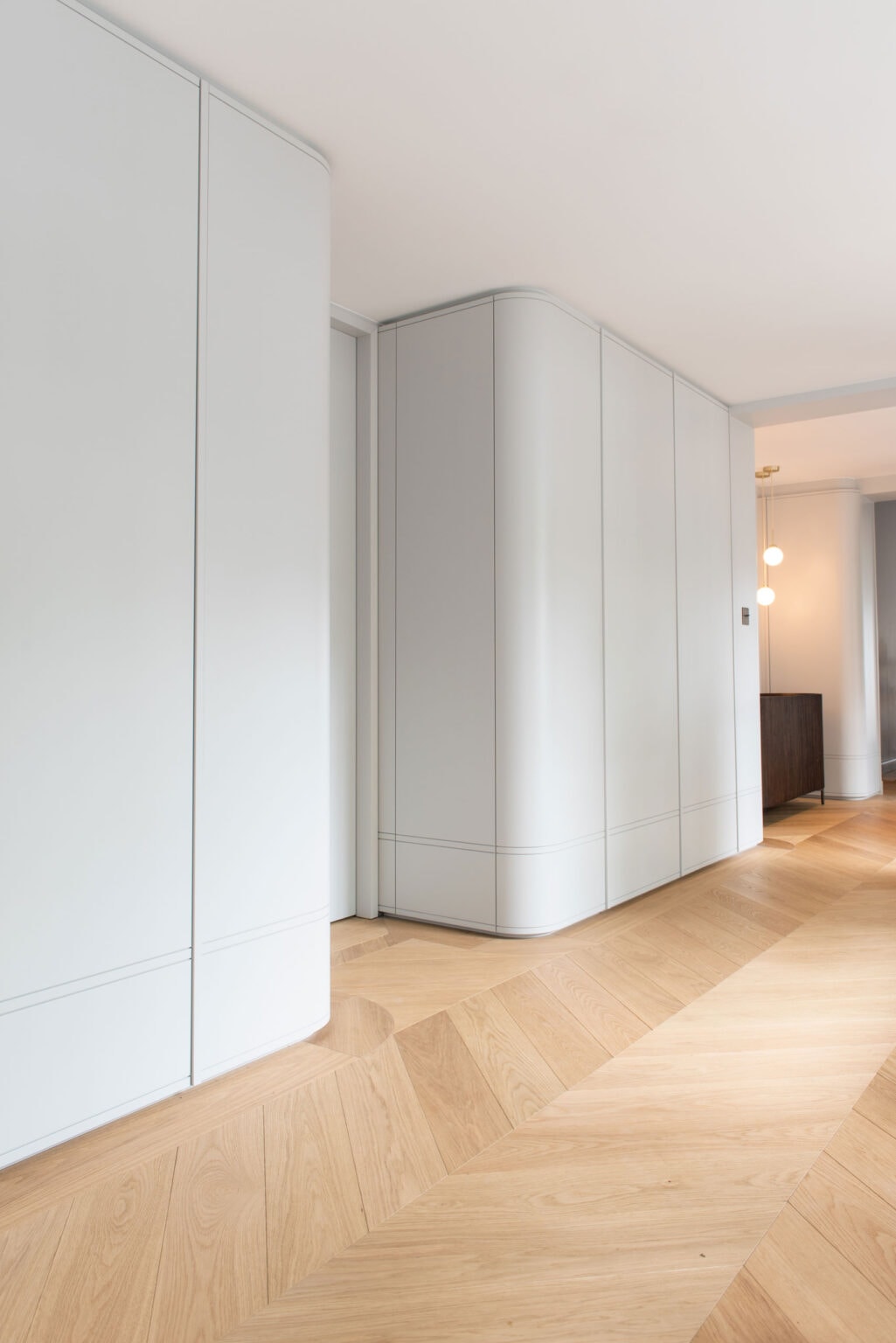 Projekt: Modern Living – grifflose weiße Einbauschränke mit gerundeter Ecke im Flur