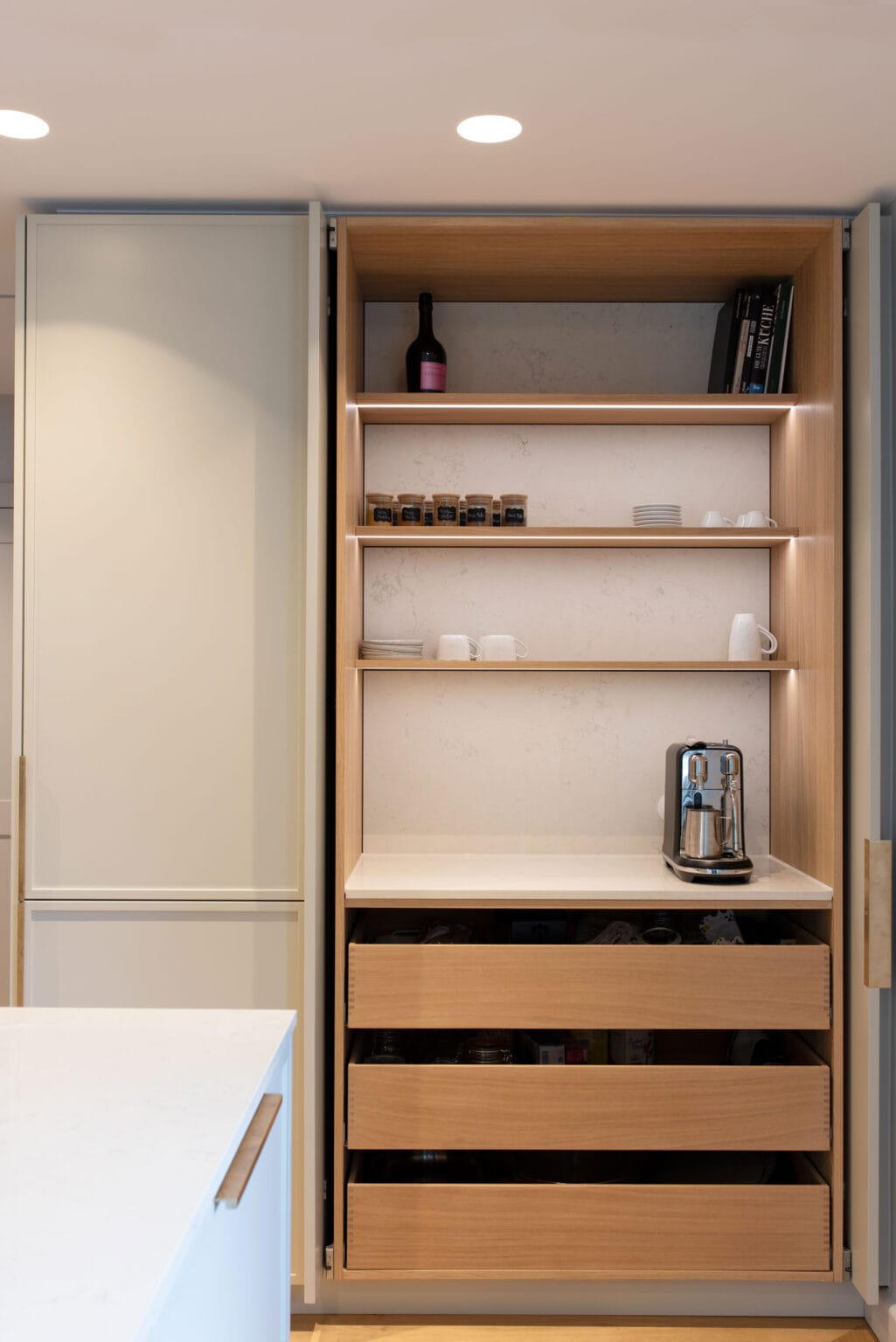 Küche mit Biancone-Marmor – geöffneter Hochschrank mit Holzregal und Schubladen