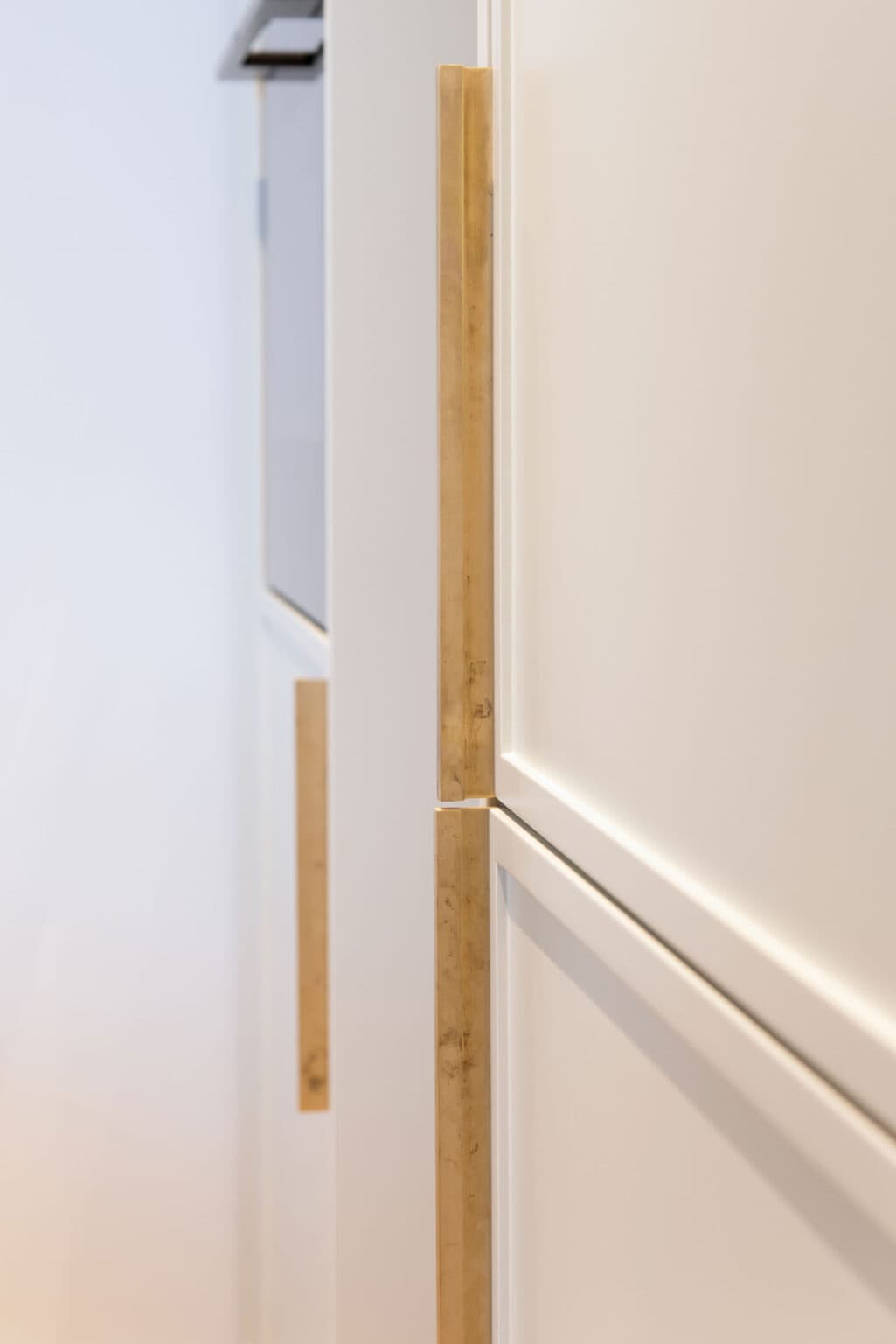 Küche mit Biancone-Marmor – Detail: Griffleisten in Holz an hellen Fronten