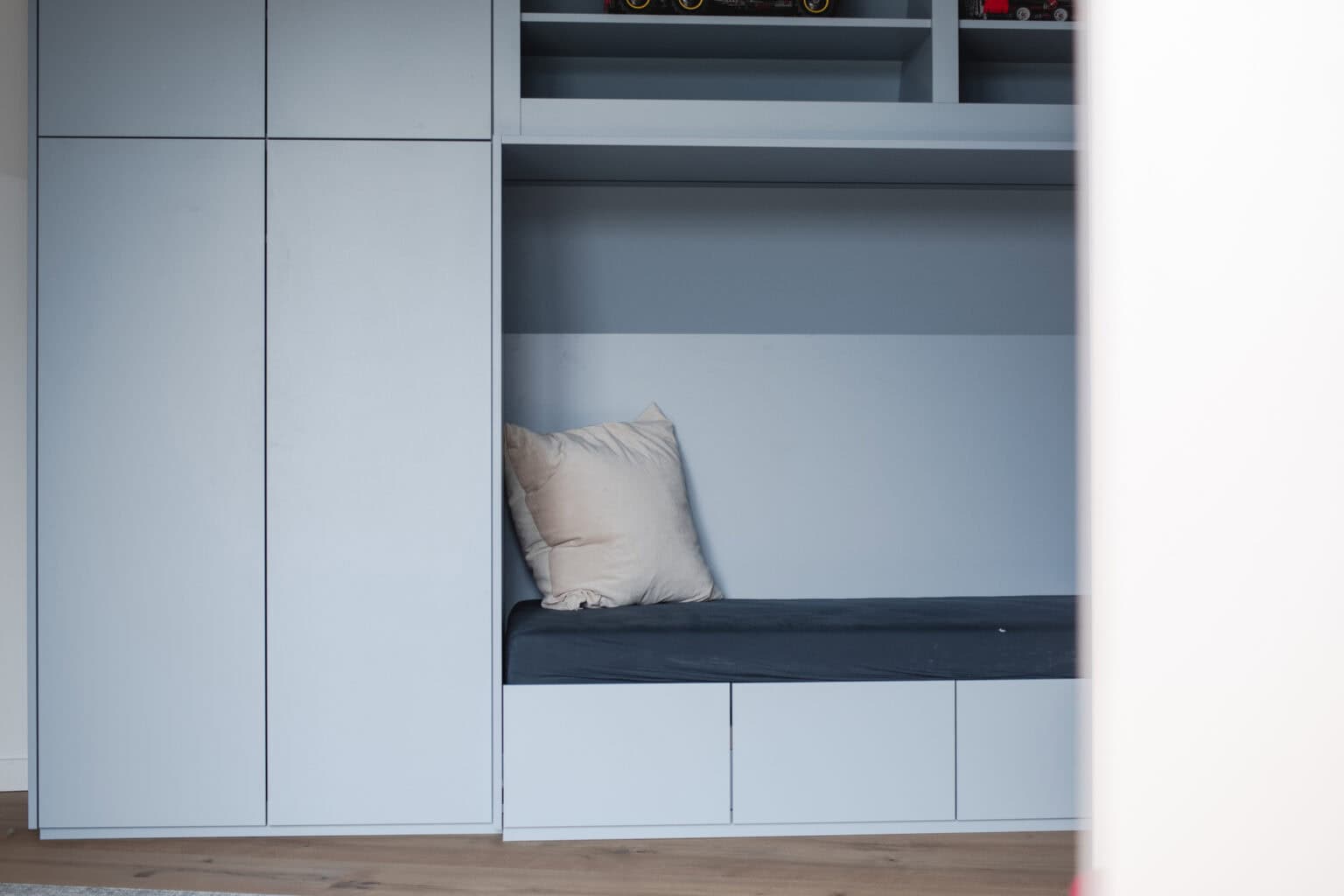 Kinderzimmer für kleine Gäste – blaugrauer Einbauschrank mit Sitznische und offenen Fächern