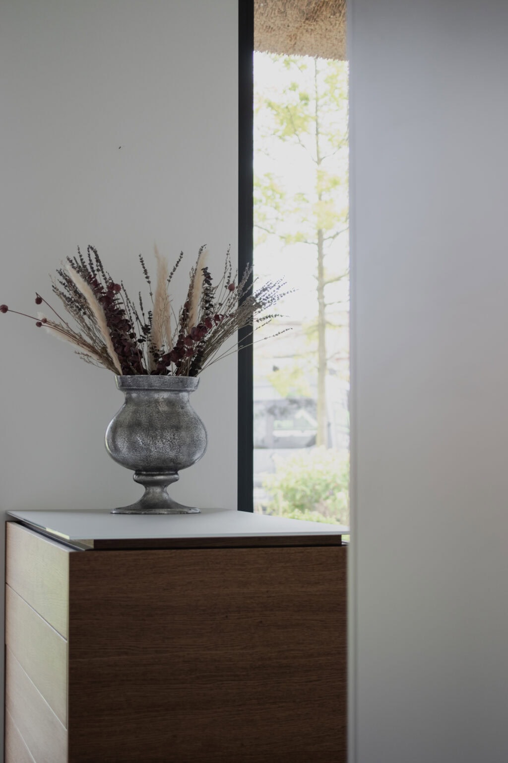 Elegantes Ankleidezimmer – Holzkommode mit Vase vor dem Fenster