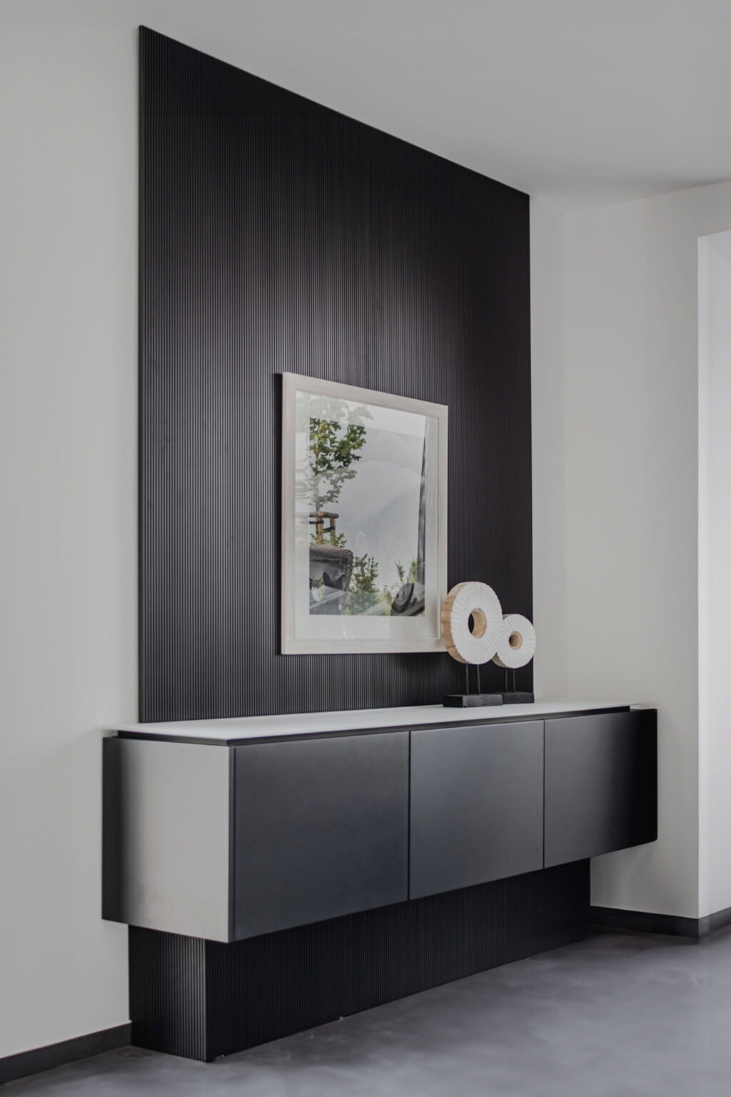 Projekt: Exklusives Wohnen an der Schlei – schwebendes Sideboard vor dunkler Rillenwand
