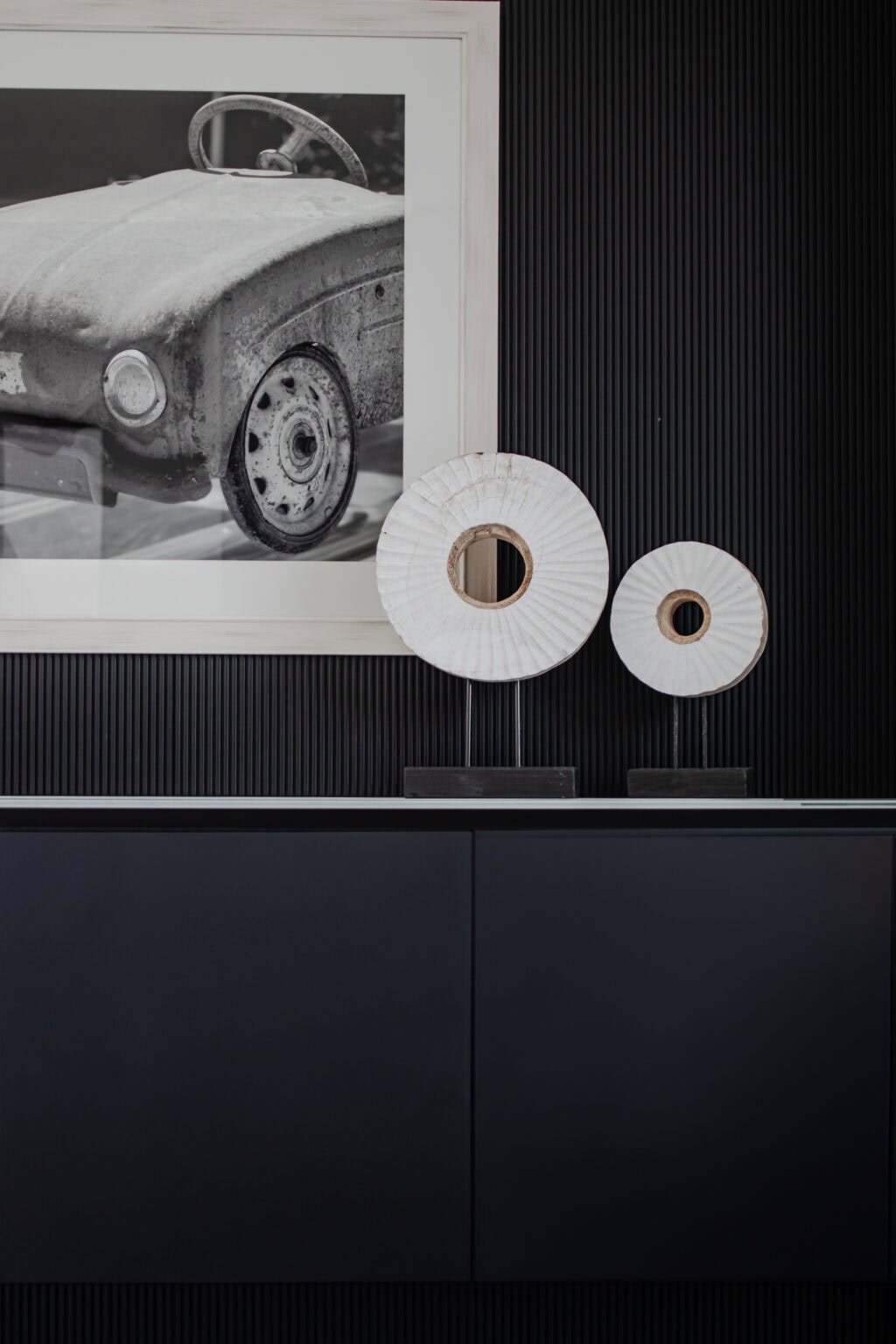 Projekt: Exklusives Wohnen an der Schlei – Detail: dunkles Sideboard vor Rillenwand mit Bild