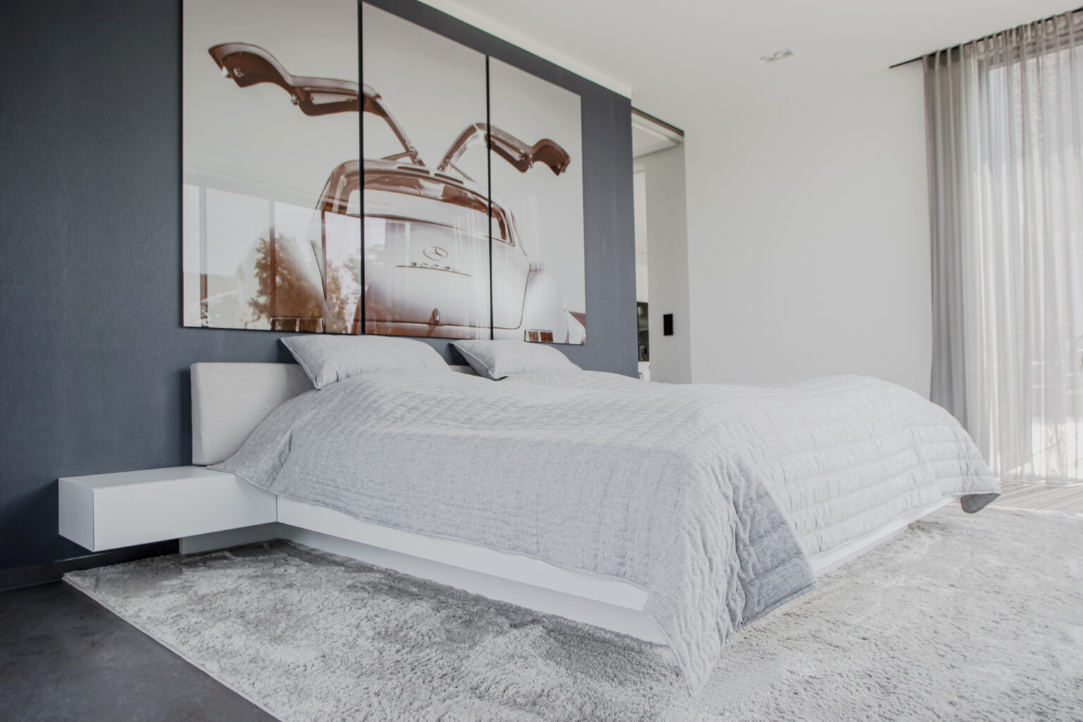 Projekt: Exklusives Wohnen an der Schlei – Bett vor dunkler Wand mit Bild und Nachttisch