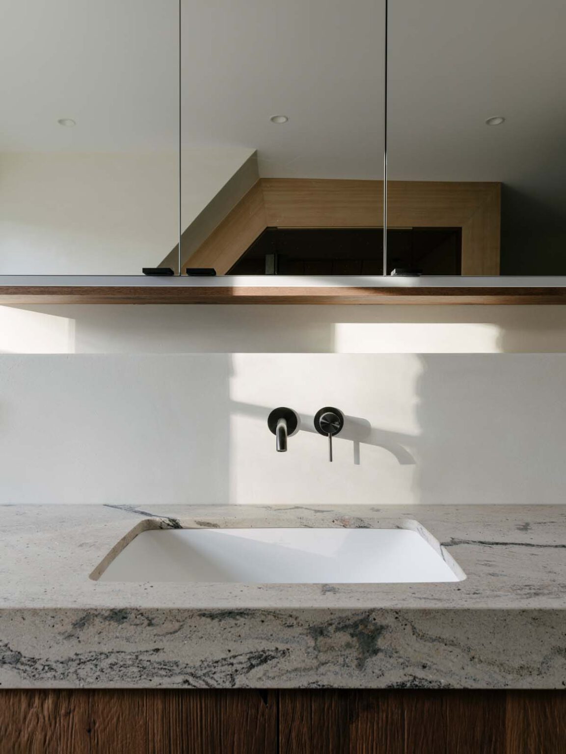 Masterbad mit Sauna – Detail: Waschbecken in gemaserter Steinplatte unter dem Spiegelschrank