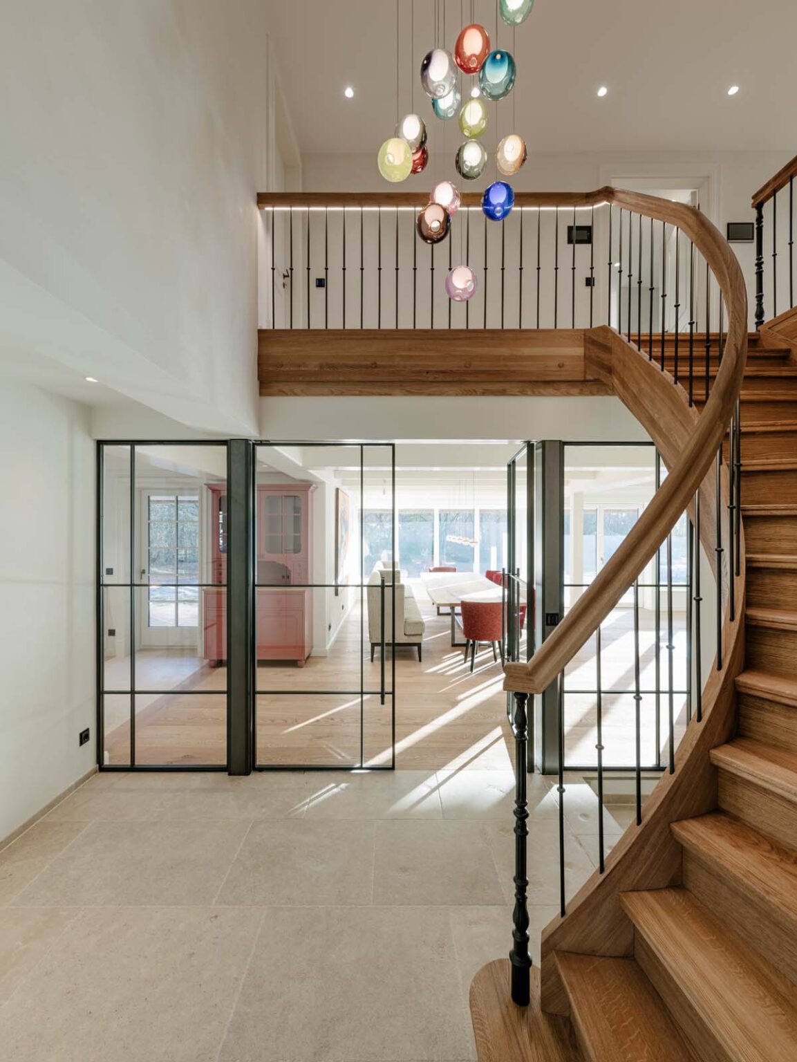 Projekt: Modernes Landhaus – geschwungene Holztreppe mit Galerie und bunter Kugelleuchte