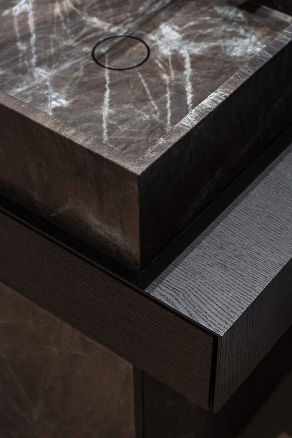 Crafted in Stone Gästebad – Detail: Ecke des Steinbeckens über der Holzkonsole
