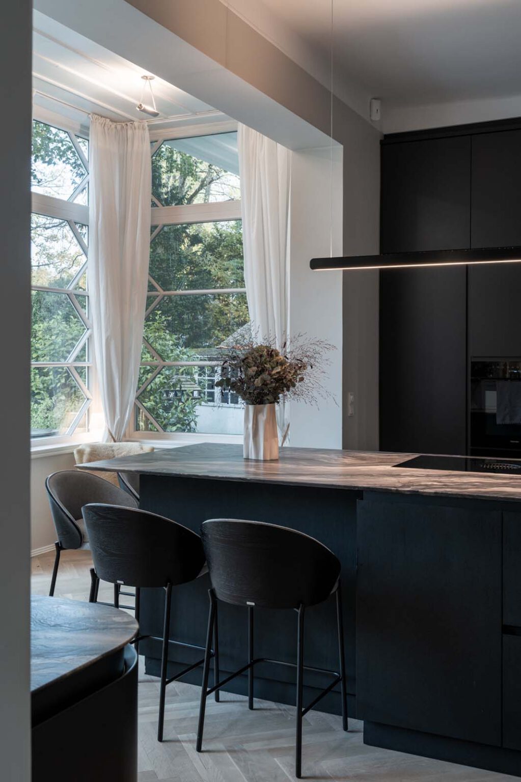 Küche: Black Kitchen – Kochinsel mit Barhockern vor dem Fenster