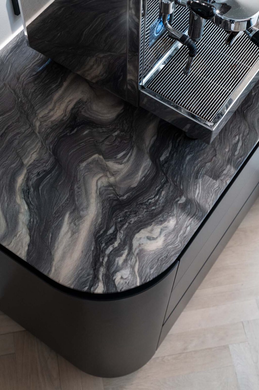 Küche: Black Kitchen – Detail: abgerundete Ecke der Kochinsel mit Steinplatte