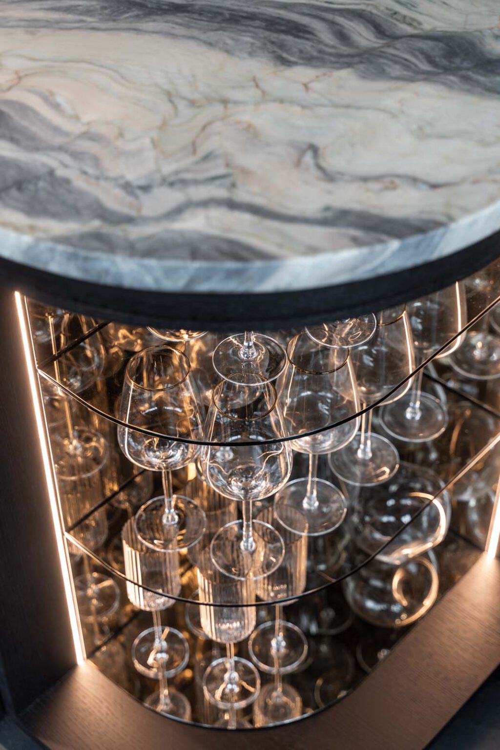 Küche: Stone meets Oak – Detail: beleuchtete Rundvitrine mit Gläsern unter der Steinplatte
